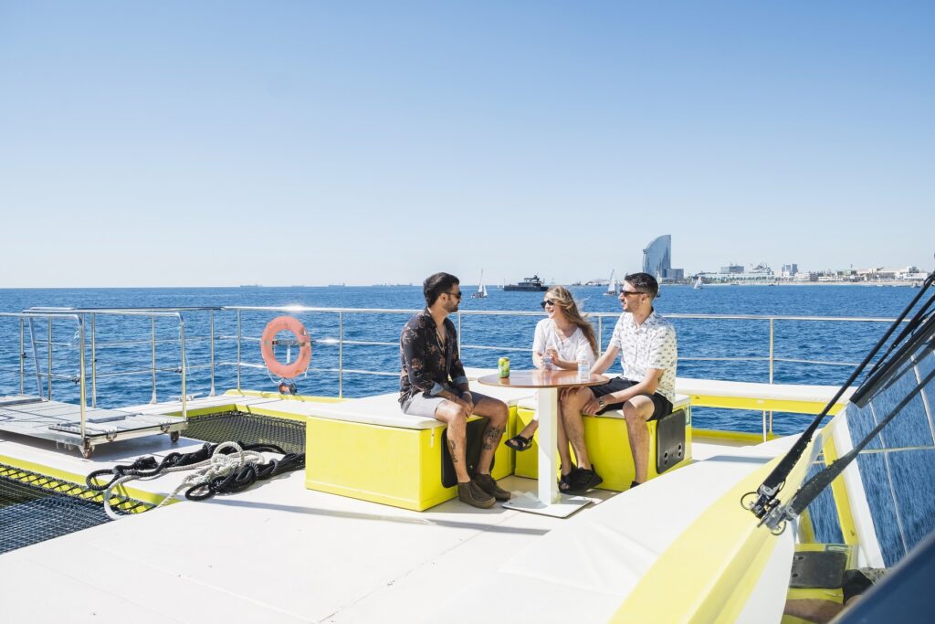Friends relaxing sitting on a table on the eco-catamaran 
